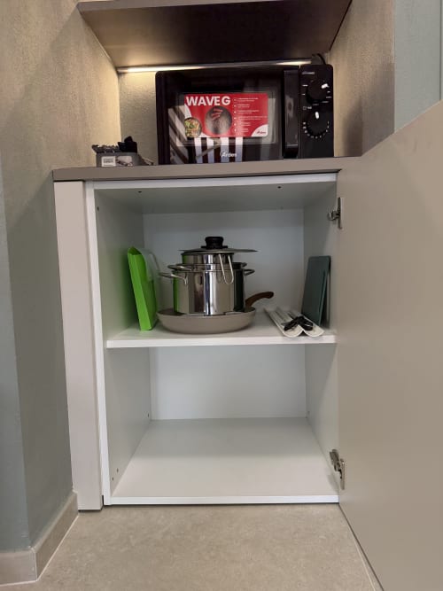 Cucina bianca con batteria di pentole e utensili, microonde in alto, appartamento La Casetta dei Ronchi a Marina di Massa