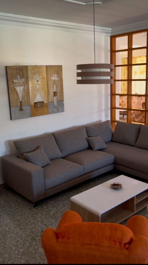 Sala moderna de Villa la Higuera con sofá gris modular, lámpara colgante y obra floral