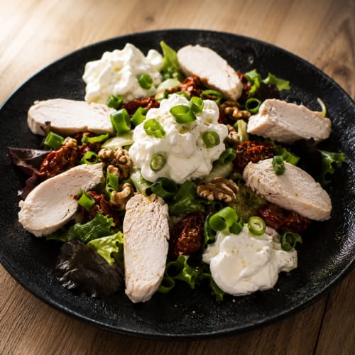 Salade gourmande au poulet tranchée, fromage de chèvre, noix, tomates séchées et oignons verts à l'Auberge La Source Bleue