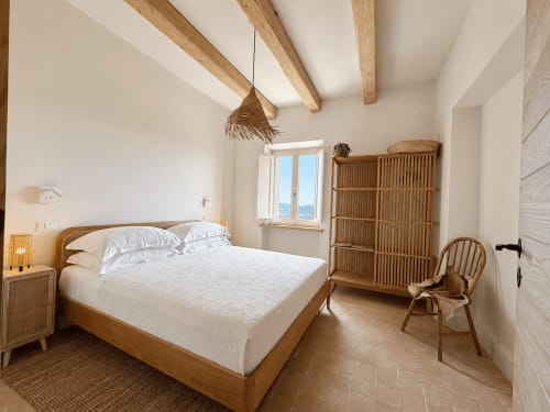 Bright bedroom at Tuscan Townhouse with wooden beams, rattan furniture, and garden views