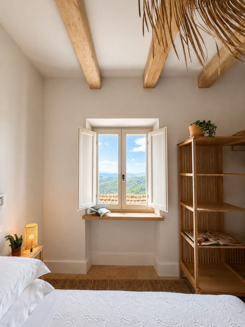 Bright bedroom at Tuscan Townhouse with open windows overlooking green hills, wooden beams, white bedding, and wooden