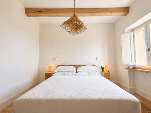Bright bedroom at Tuscan Townhouse with double bed, wooden beams, pendant light, and garden view from windows