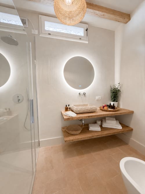 Modern bathroom with illuminated round mirror, floating wooden vanity, and walk-in shower at Tuscan Townhouse, Montemassi
