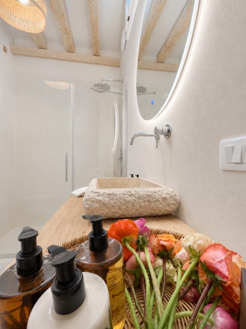 Modern bathroom with natural wood beams, vessel sink, and fresh flowers at Tuscan Townhouse