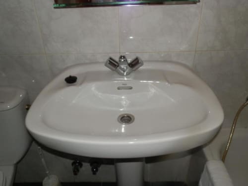 Lavamanos blanco pedestal con grifo cromado en baño del Hostal San Poul, habitación del hotel Consuegra