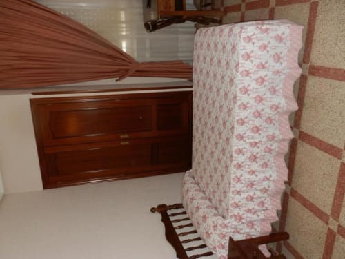 Habitación individual en Hostal San Poul de Consuegra con cama de flores rosas, muebles de madera, suelo de azulejos y detalles de pared de ladrillo