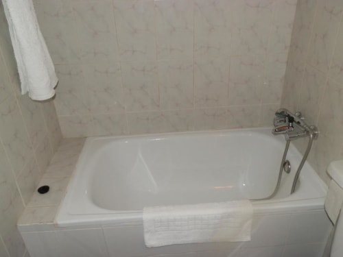 Baño limpio con bañera blanca, ducha y toallero en el Hostal San Poul de Consuegra, España