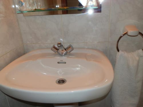 Lavabo moderno con grifo cromado y espejo en el Hostal San Poul de Consuegra, España