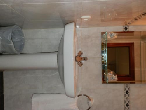 Baño de la Habitación Cuádruple en Hostal San Poul, Consuegra con inodoro, lavabo, espejo y paredes alicatadas