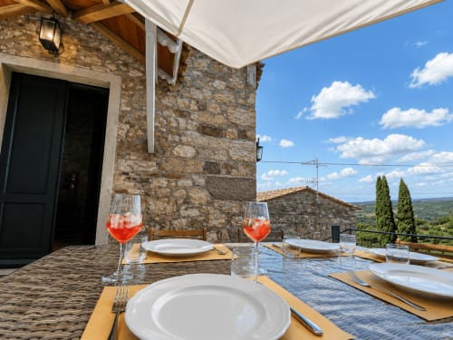 Tuscan stone terrace dining setup with aperitivos, overlooking garden and countryside near Montemassi, Italy