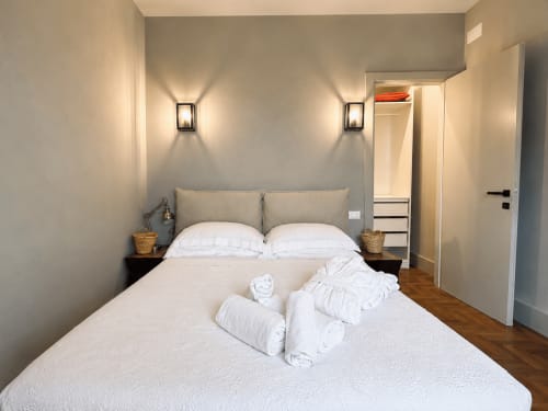 Modern bedroom in Tuscan Townhouse Garden Suite with white pillows, bedside tables, wall sconces, and ensuite bathroom