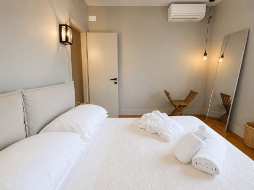 Modern bedroom in Tuscan Townhouse Garden Suite with white bedding, wooden floor, air conditioning, and contemporary