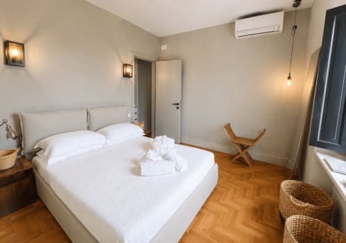 Bright Garden Suite bedroom at Tuscan Townhouse with white bed, wooden floor, AC unit, and garden access in Montemassi