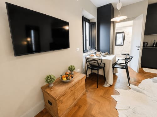 Modern Garden Suite at Tuscan Townhouse with wall-mounted TV, dining table, wooden dresser, and kitchen in Montemassi