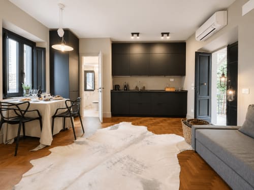Modern Garden Suite at Tuscan Townhouse with black kitchen, dining area, sofa, and herringbone wood floors
