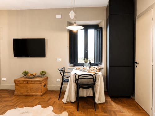 Modern dining area in Garden Suite at Tuscan Townhouse with round table, black chairs, TV, and garden view doors