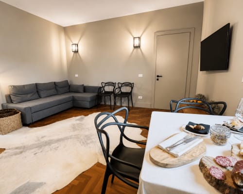 Modern Garden Suite at Tuscan Townhouse with gray sofa, dining table, and wall-mounted TV in Montemassi