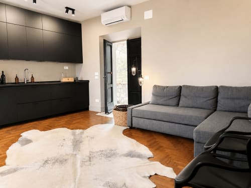 Modern Garden Suite living area at Tuscan Townhouse with gray sofa, black kitchen, wooden floors, and garden view entrance