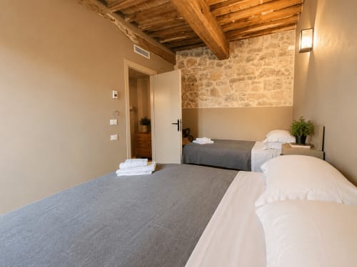 Tuscan Townhouse Club apartment in Montemassi with twin beds, exposed beams, and stone walls