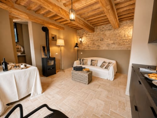 Tuscan townhouse living room with exposed beams, fireplace, white sofa, and terracotta floors in Montemassi