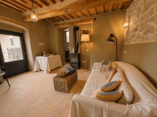 Rustic Tuscan townhouse apartment with beamed ceiling, cream sofa, fireplace, and warm lighting in Montemassi