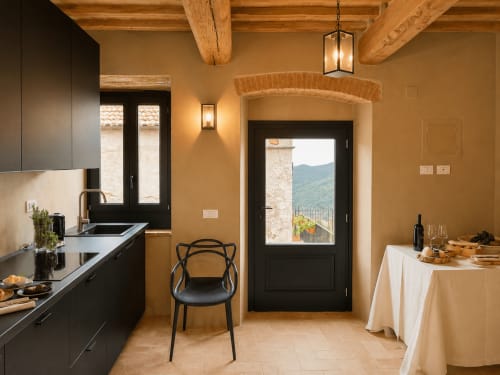 Tuscan townhouse kitchen with black cabinetry, exposed wooden beams, archway, and mountain view through door