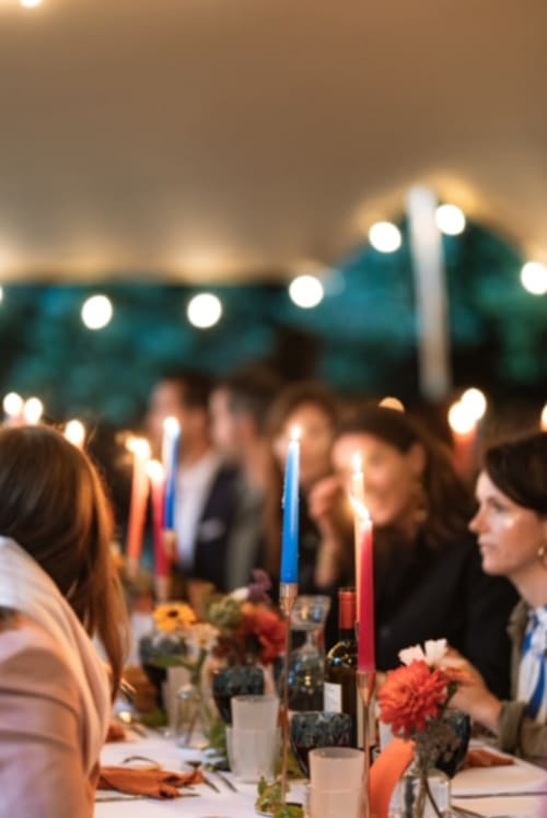 Evening garden dinner at Chateau de Moulins with candlelit table, guests, and twinkling lights