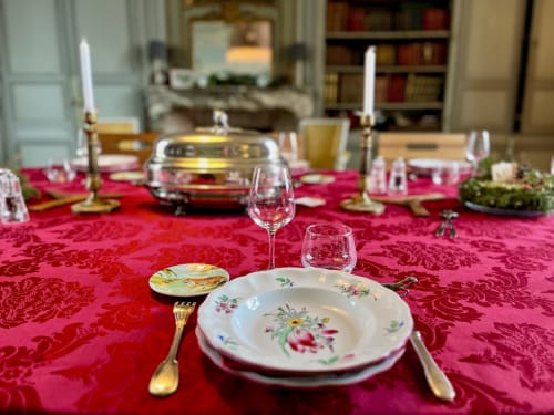 Elegant formal dining setup at Chateau de Moulins with pink damask tablecloth, floral plates, and candlelit table setting