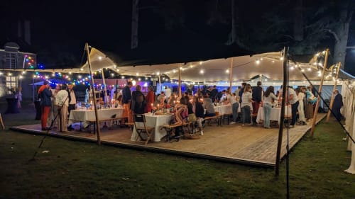 Outdoor evening event tent at Chateau de Moulins with guests dining and socializing under string lights in garden
