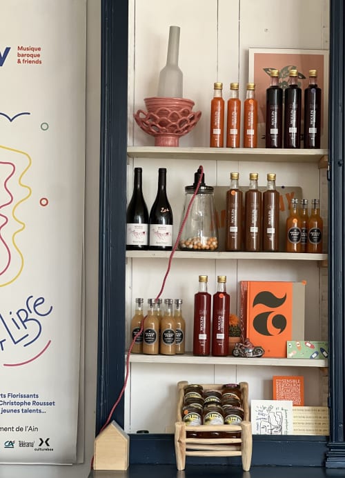 Liqueurs artisanales et conserves exposées sur les étagères de La Maison d'Ambronay, une maison d'hôtes française.