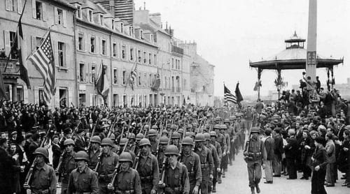 Historical WWI military parade with soldiers marching through French town square, American flags visible