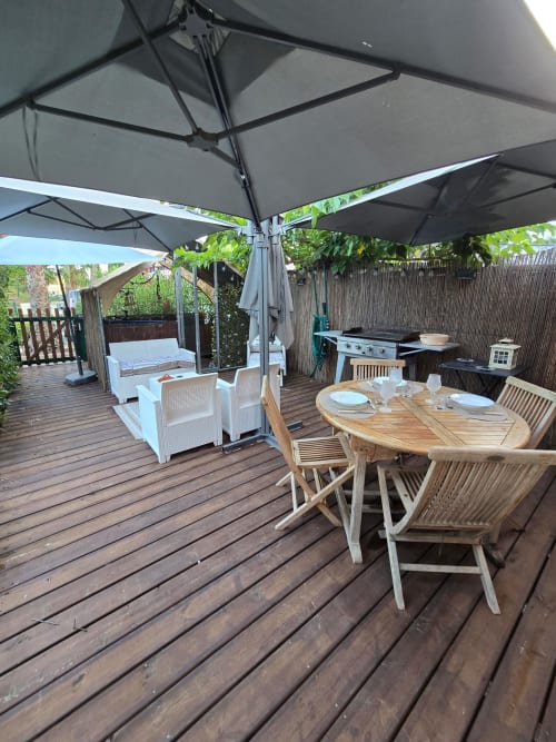 Grande terrasse La Montagnette avec table à manger, salon de détente, barbecue et parasols à Cap d'Agde