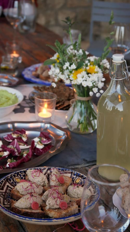 Dîner élégant en plein air au Mas des Ecoliers avec amuse-bouches, composition florale, bouteille de vin et lumière aux chandelles en Provence.