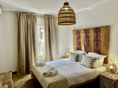 Quarto aconchegante no hotel Ocean House Alentejo em Porto Covo com cabeceira tecida, luminária pendente e vista para a cidade