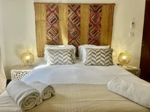 Quarto Vasco da Gama na Ocean House Alentejo, Porto Covo, com cama, cabeceira geométrica, toalhas enroladas e luminárias douradas