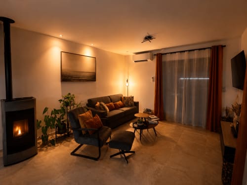 Salon luxueux de villa avec cheminée, sièges confortables et éclairage ambiant chaleureux en Corse