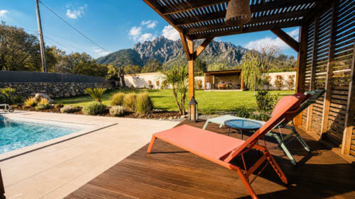 Transats orange sous pergola à la piscine de Villa Cinto, montagnes corses en arrière-plan