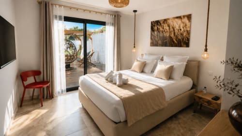 Chambre élégante aux Villas Vallée d'Asco avec vue sur la piscine, literie blanche, accès terrasse et fauteuil rouge