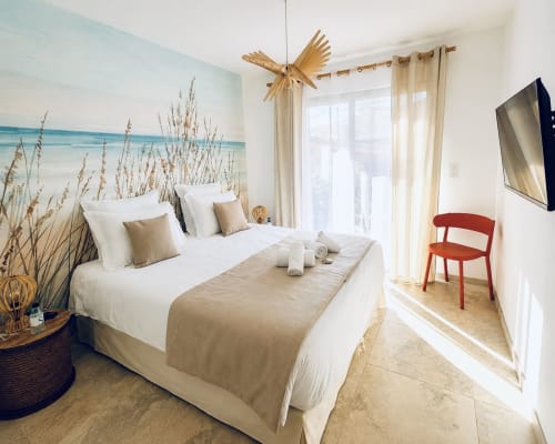 Chambre luxueuse à la Villa Capu Biancu avec fresque murale thème marin, literie blanche, décor doré et accès vue mer