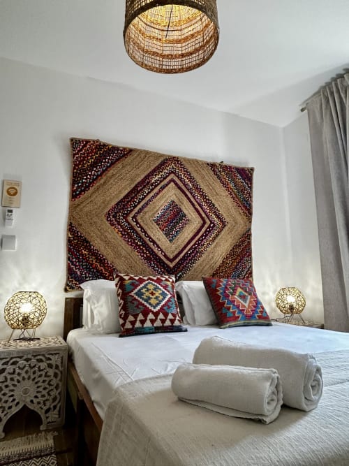 Quarto da Ocean House Alentejo com decoração boêmia, tapete estampado na parede e toalhas enroladas na cama