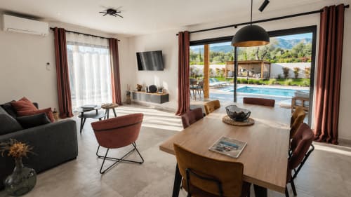 Villa contemporaine avec séjour ouvert, vue sur piscine en Corse, coin repas et salon aux touches rouges