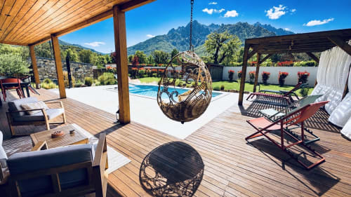 Terrasse piscine d'une villa corse de luxe avec chaises suspendues, vue sur les montagnes, pergola en bois et piscine chauffée aux Villas Vallée d'Asco