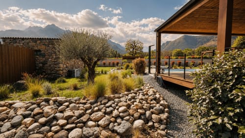 Terrasse de la Villa Capu Biancu avec piscine chauffée, patio en pierre, olivier et vue sur les montagnes en Corse
