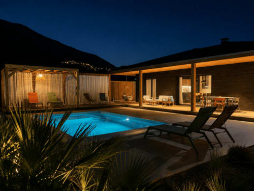 Villa de luxe avec piscine chauffée en Corse au crépuscule, terrasse illuminée, transats et vue sur les montagnes