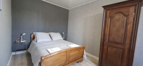 Chambre à l'Accolade Châteaudun avec lit en bois, draps blancs, mur d'accent bleu et armoire en bois