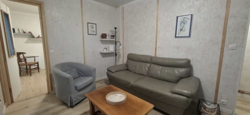 Salon cosy de l'hôtel Accolade à Châteaudun avec canapé gris, fauteuil et table basse en bois
