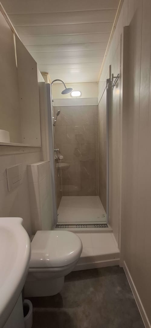 Salle de bain moderne à l'Accolade Châteaudun avec toilettes, douche et éclairage lumineux