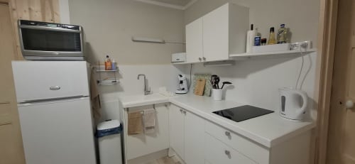 Kitchenette moderne de l'appartement Accolade à Châteaudun, avec meubles blancs, micro-ondes, plaque de cuisson et électroménagers