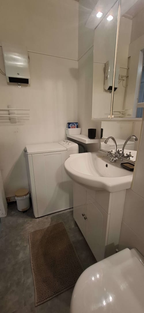 Salle de bain moderne à l'hôtel Accolade de Châteaudun avec lavabo sur colonne, toilettes, armoire miroir et articles de toilette sur le comptoir