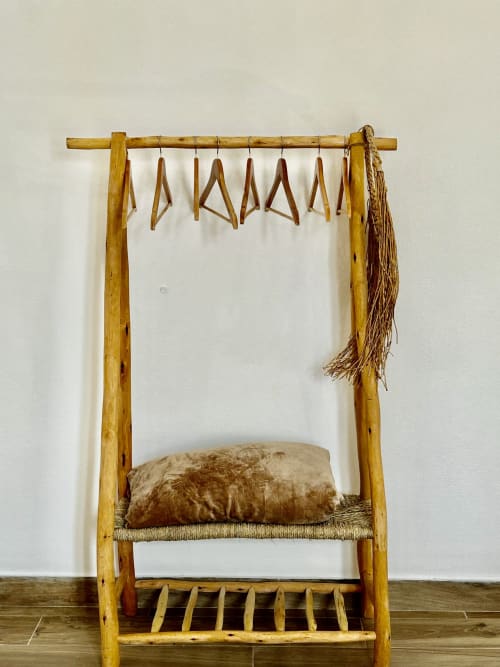 Cama rústica em madeira com assento tecido, cabideiros de madeira suspensos e cesto trançado na Ocean House Alentejo em Porto Covo,